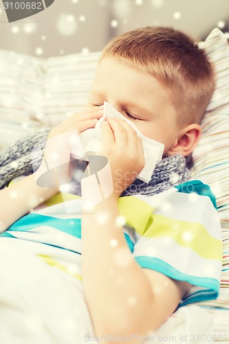 Image of ill boy blowing nose with tissue at home