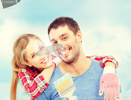 Image of smiling couple covered with paint with paint brush