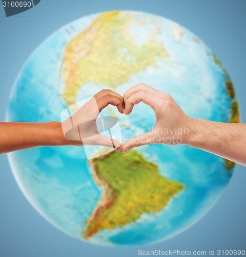 Image of human hands showing heart shape over earth globe