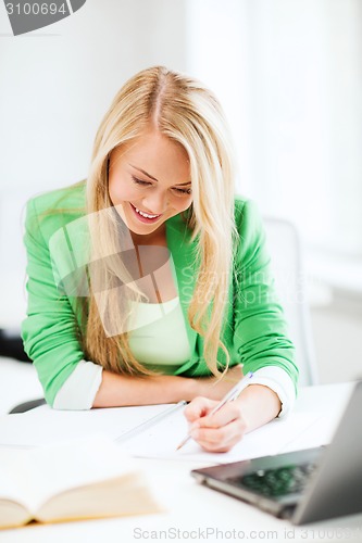 Image of smiling student girl writing in notebook