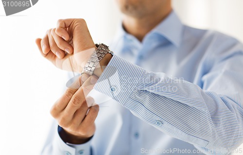 Image of close up of man in shirt fastening wristwatch