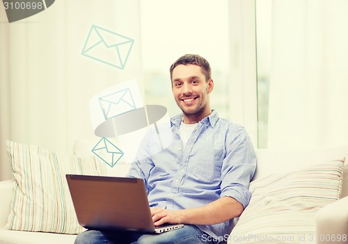 Image of smiling man working with laptop at home