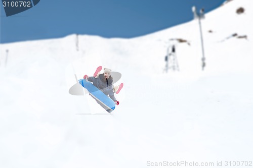 Image of happy teenage girl sliding down on snow tube