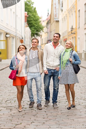 Image of group of smiling friends walking in the city