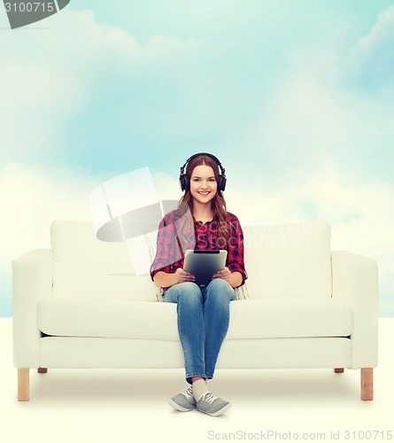 Image of girl sitting on sofa with headphones and tablet pc