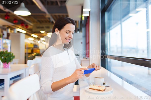 Image of smiling woman with smartphone and coffee at cafe