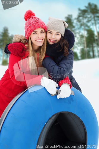 Image of happy girl friends with snow tubes outdoors