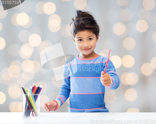 Image of happy little girl drawing with coloring pencils