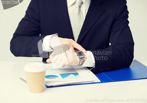 Image of businessman with graphs pointing at watch