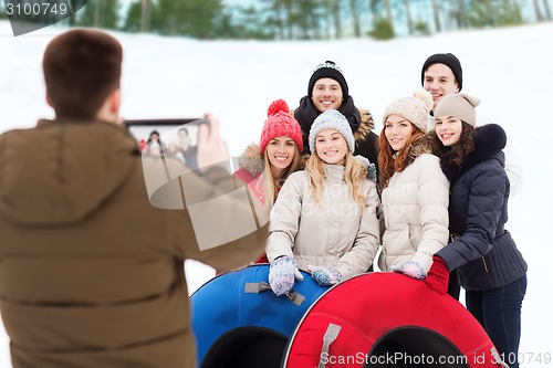 Image of group of smiling friends with snow tubes