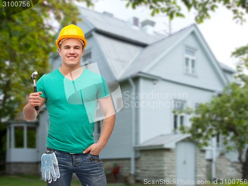 Image of smiling manual worker in helmet with hammer