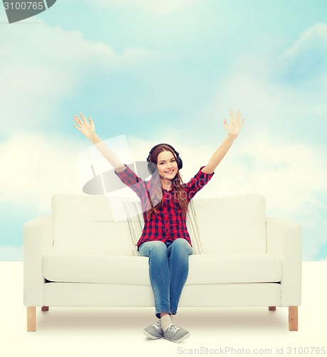 Image of teenage girl sitting on sofa with headphones