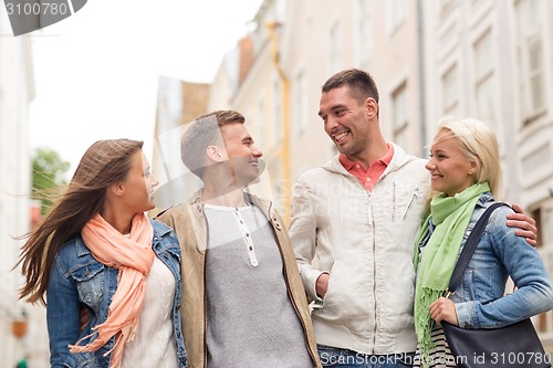 Image of group of smiling friends walking in the city