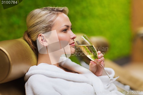 Image of beautiful young woman drinking champagne at spa