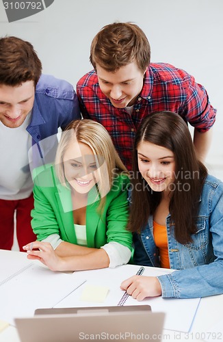 Image of smiling students looking at laptop at school