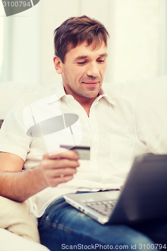 Image of man with laptop and credit card at home