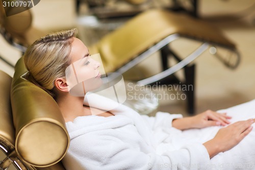 Image of beautiful young woman sitting in bath robe at spa