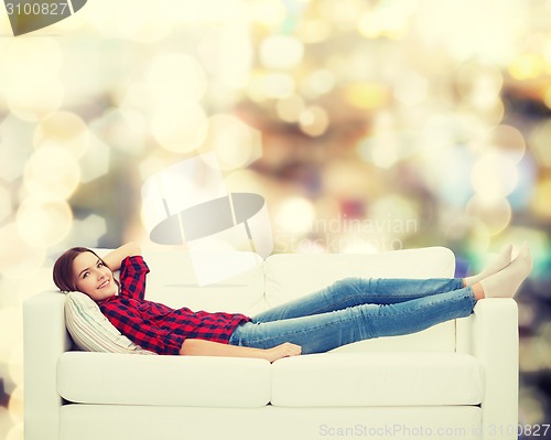 Image of smiling teenage girl lying on sofa