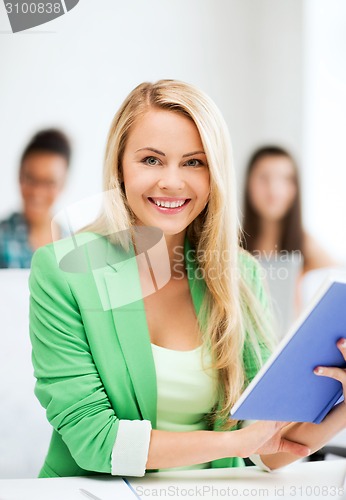 Image of smiling young girl reading book at school