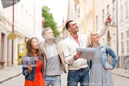 Image of group of smiling friends with city guide and map