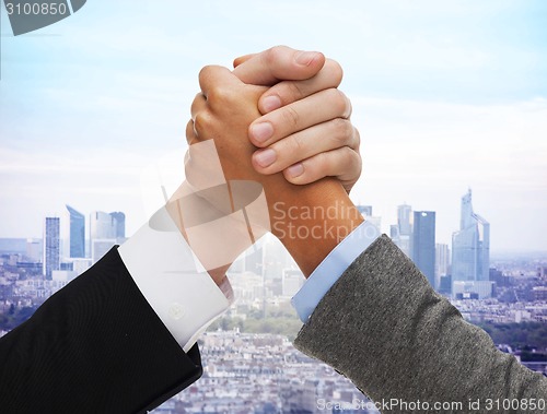 Image of close up of hands arm wrestling over city