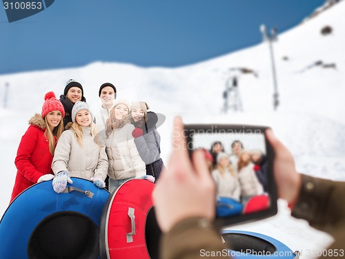 Image of smiling friends with snow tubes and tablet pc