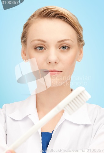 Image of happy young female dentist with tooth brush