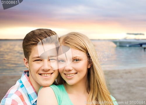 Image of smiling couple hugging over beach background