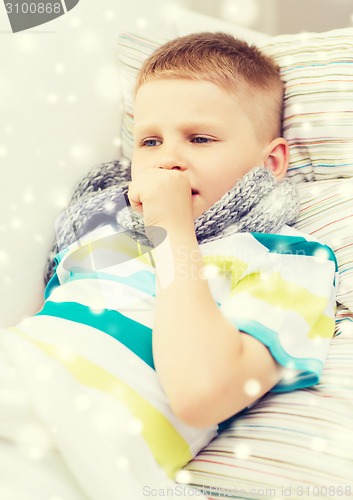 Image of ill boy with scarf lying in bed and coughing