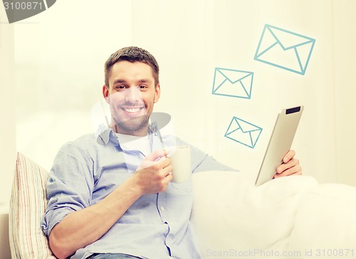 Image of smiling man working with tablet pc at home