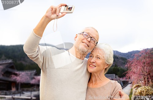 Image of senior couple with camera over asian village