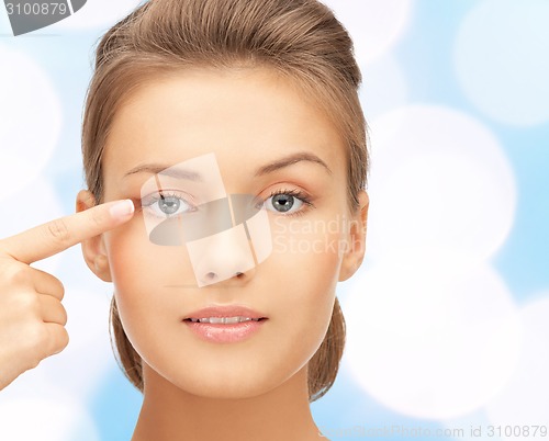 Image of beautiful young woman pointing finger to her eye