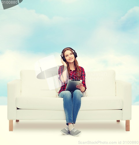 Image of girl sitting on sofa with headphones and tablet pc