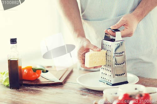 Image of close up of male hands grating cheese