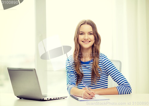 Image of smiling teenage girl laptop computer and notebook