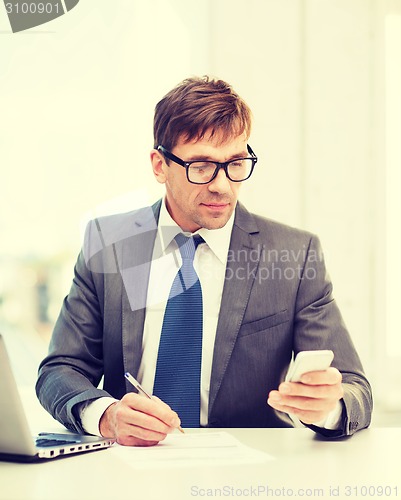 Image of businessman working with laptop and smartphone