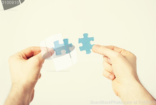 Image of two hands trying to connect puzzle pieces