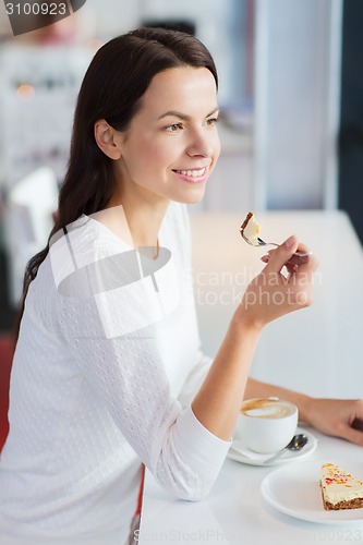 Image of smiling young woman with cake and coffee at cafe