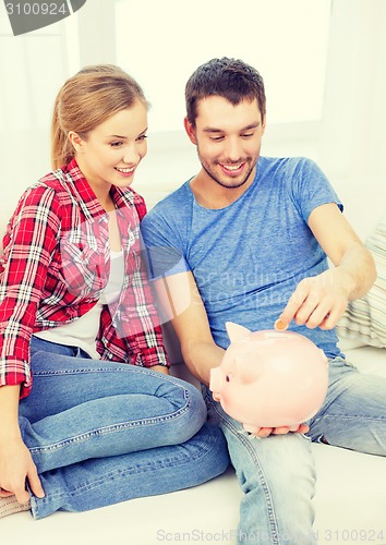 Image of smiling couple with piggybank sitting on sofa