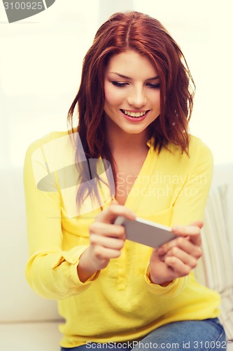 Image of smiling woman with smartphone at home