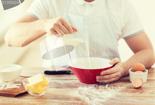 Image of close up of male hand pouring milk in bowl