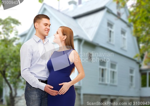 Image of happy young family expecting child over house