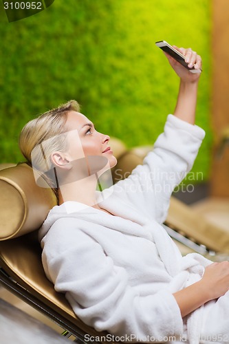 Image of beautiful young woman with smartphone at spa