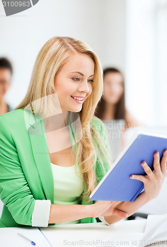 Image of smiling young girl reading book at school