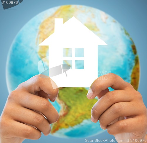 Image of couple hands holding green house over earth globe