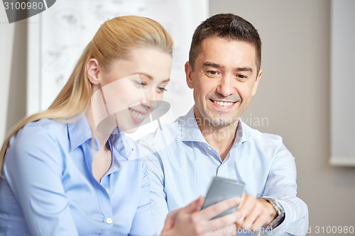 Image of smiling businesspeople with smartphones in office