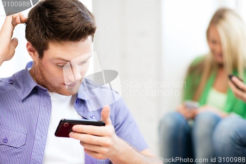 Image of student looking at phone and writing something