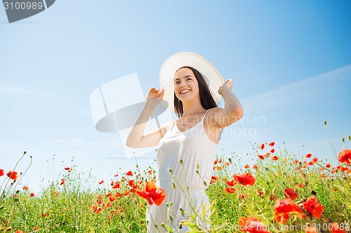 Image of smiling young woman in straw hat on poppy field