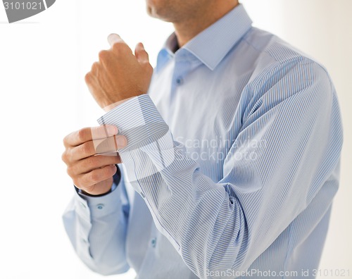 Image of close up of man fastening buttons on shirt sleeve