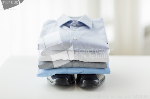 Image of close up of folded male shirts and shoes on table